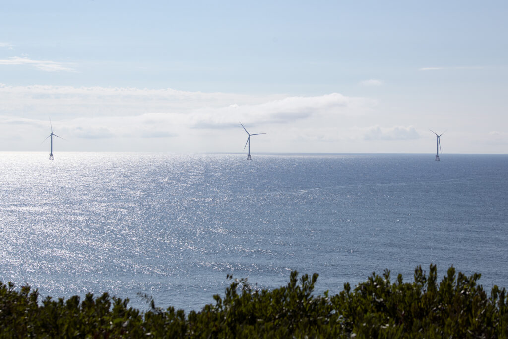 View of three offshore wind turbines from land