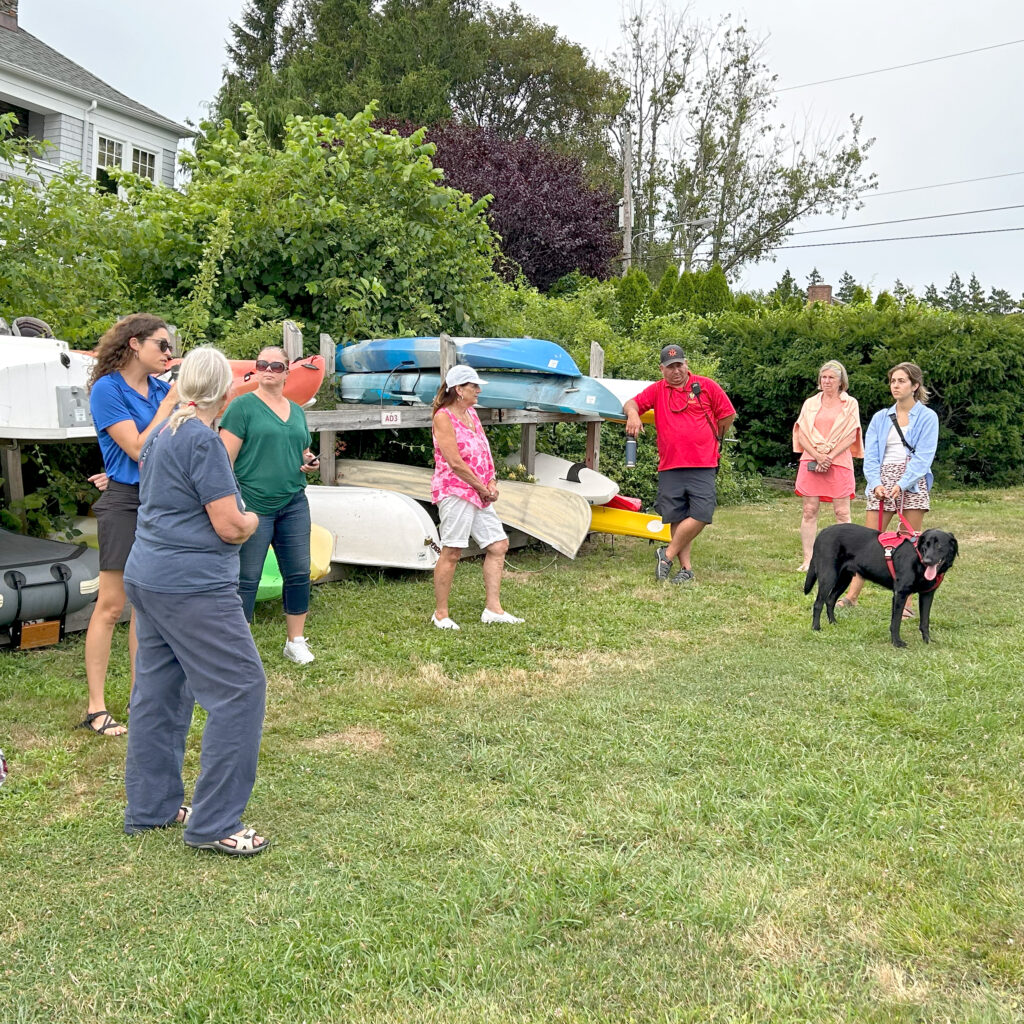 Group of people are gathered around a kayak rack