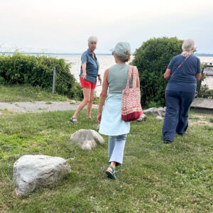 A woman points to a line large stones set in the grass
