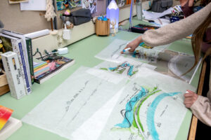 A hand points to a detail of a drawing of Mackerel Cove