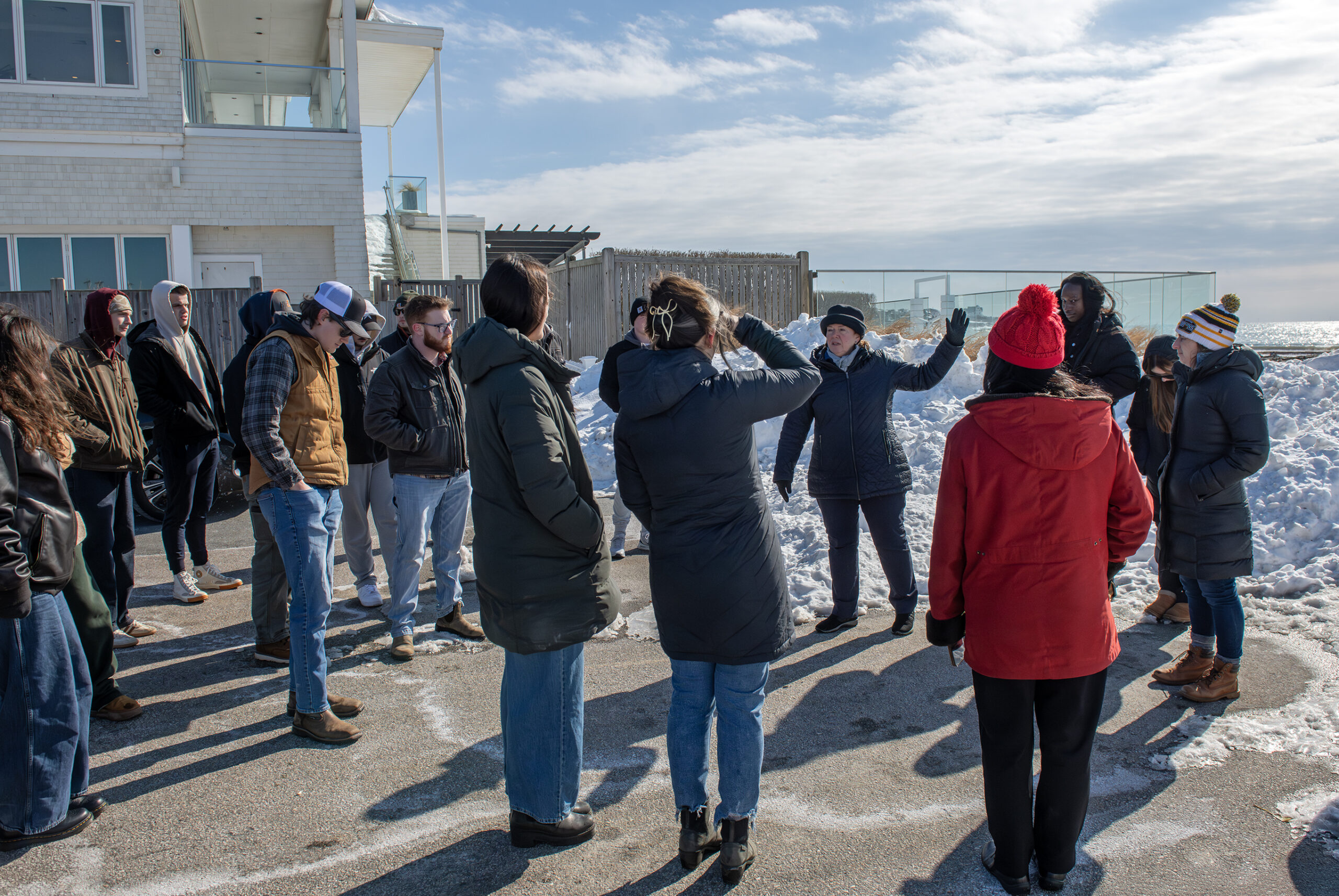 A group gathers around a person speaking near Easton's Beach access point