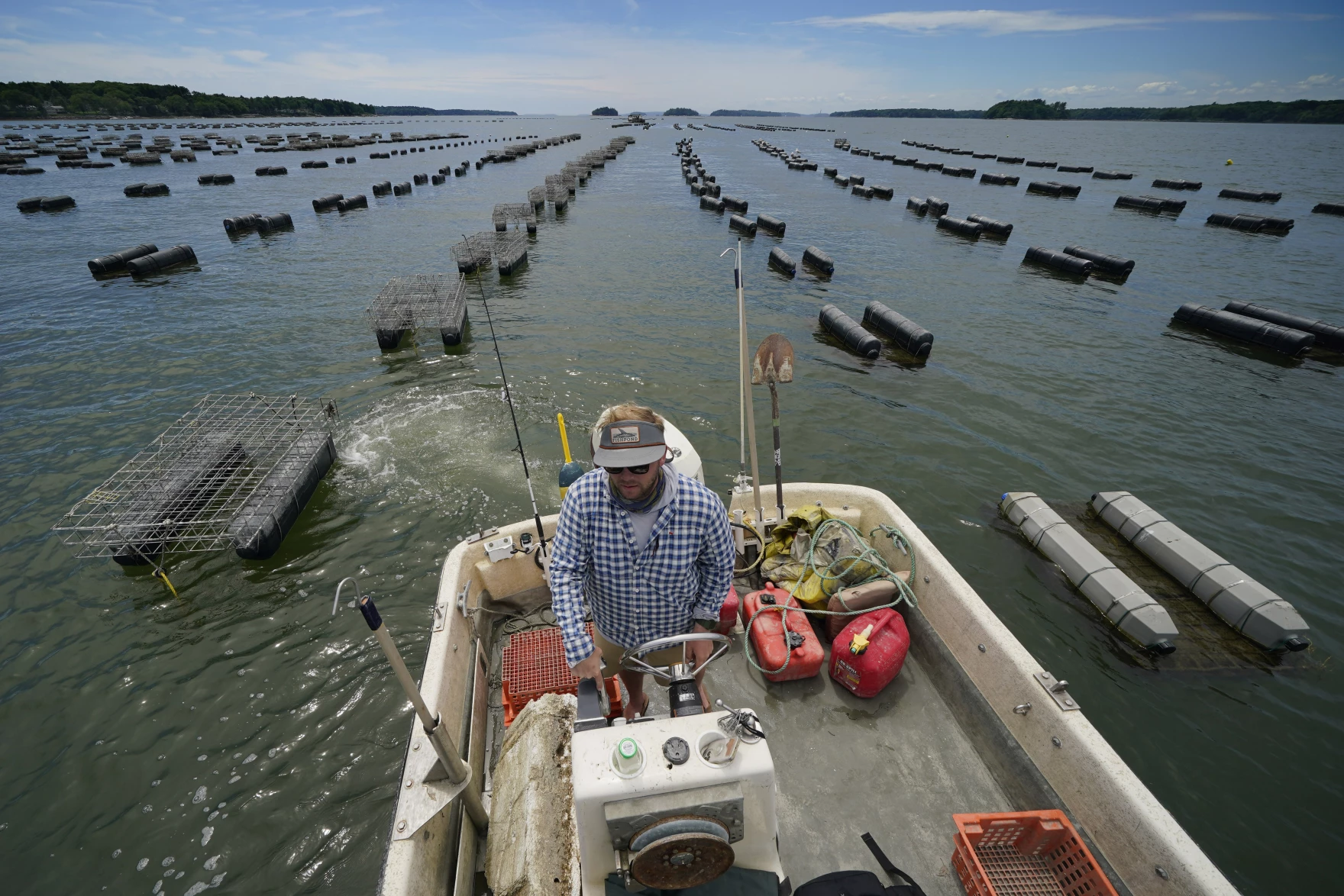 Fisherman pilots boat through a vast array of floating oyster cages on Maquiot Bay, Maine.