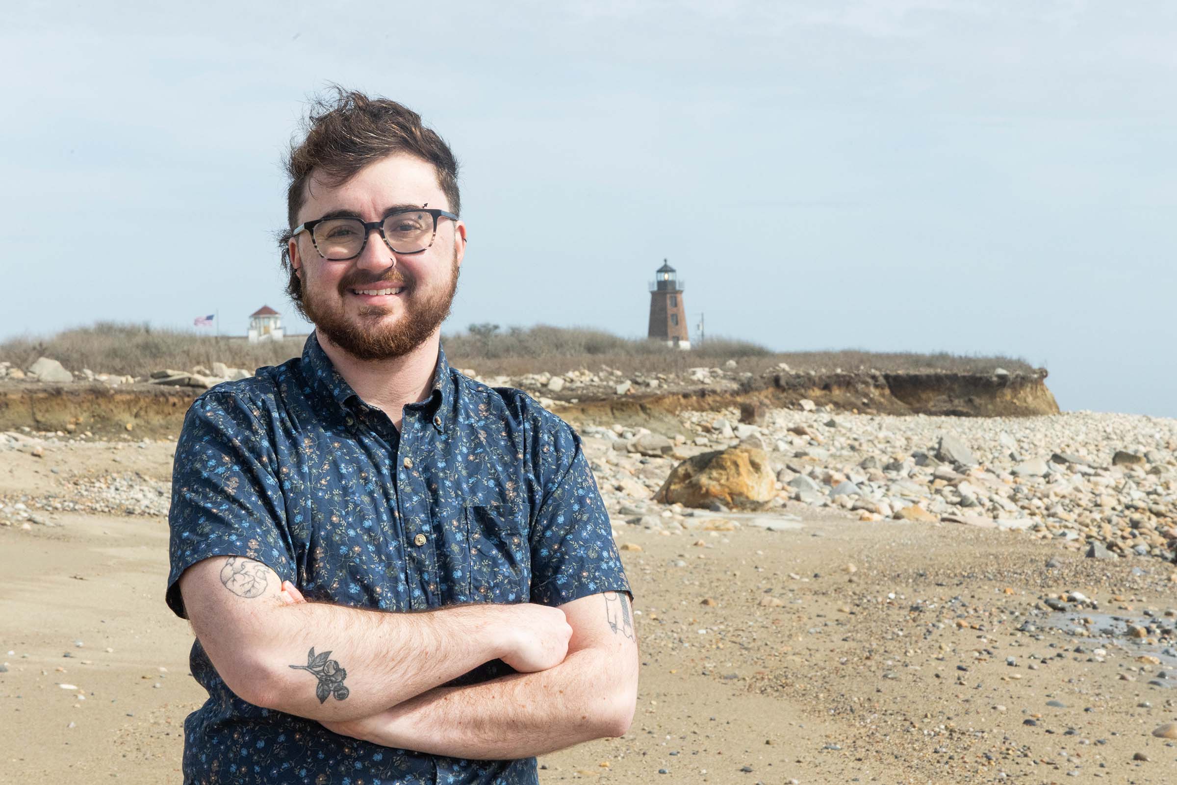 A photo of Samuel Filiaggi on the beach with a lighthouse in the background