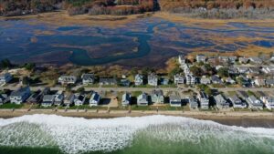 An aerial shot of houses along a beach with a marsh behind them